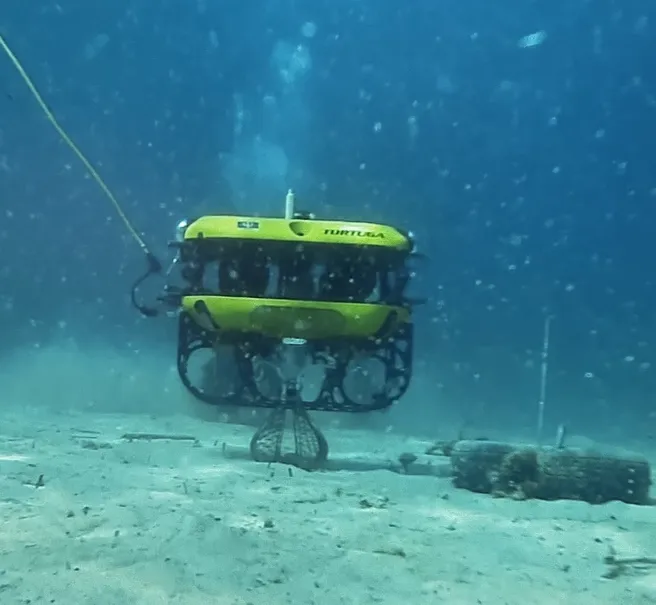 The Tortuga robot collecting a bottle from the seafloor.